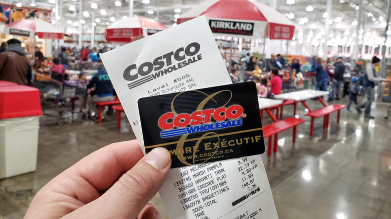 person holding a Costco card and receipt after shopping in the store