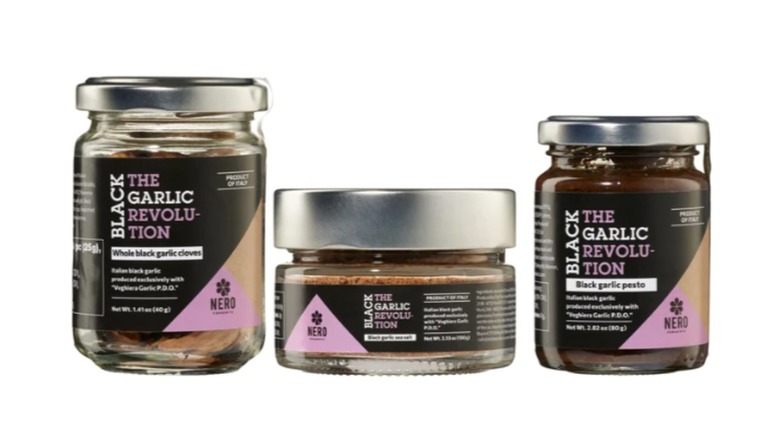 three differently sized jars containing black garlic cloves, sea salt, and pesto