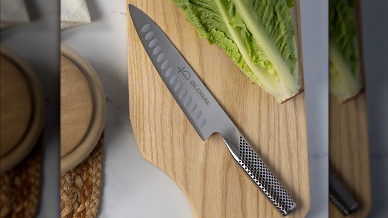 Global 40th Anniversary 7-Inch Fluted Chef's Knife on cutting board with romaine lettuce