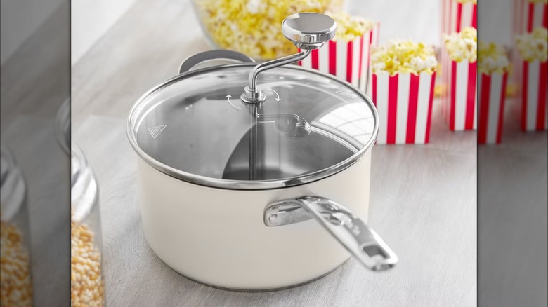 A stainless steel popcorn popper with lid and handle.