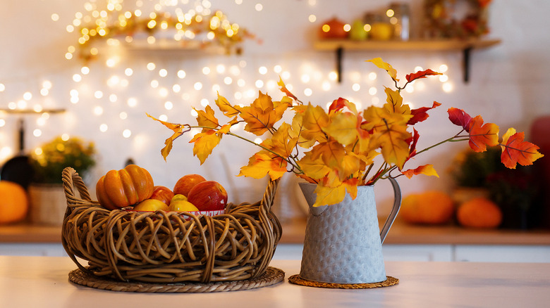 A kitchen decorated for fall with lights and autumnal centerpiece.