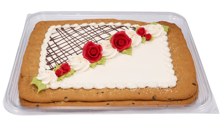 Cookie cake decorated with white icing and flowers made of frosting.