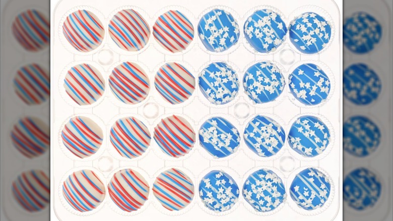 An assortment of patriotically decorated cake balls in a plastic container.