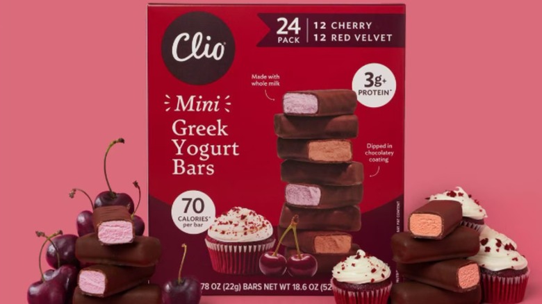 Box of Clio mini greek yogurt bars with the bars, cupcakes and cherries next to it