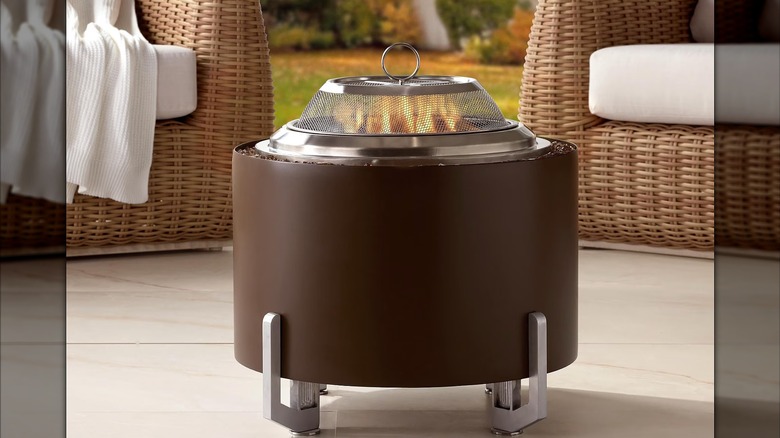 Smokeless wood fire pit pn a patio with two chairs behind it