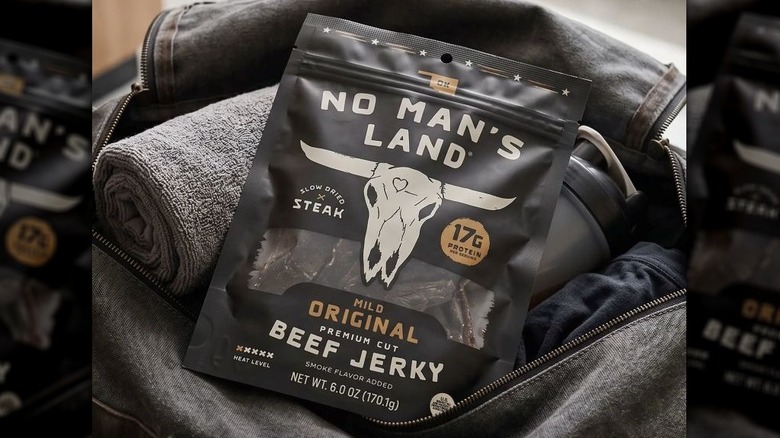 Bag of No Man's Land beef jerky on top of an open packed duffel bag