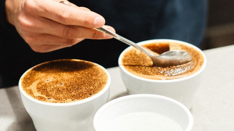 Person stirs a coffee drink in a white cup