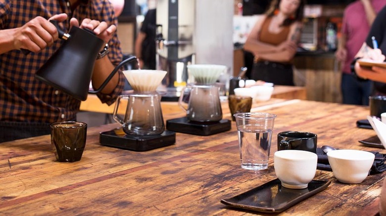 Barista pours water from a kettle into a pour-over coffee maker