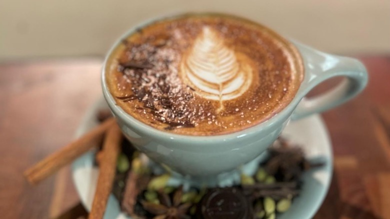 A chai with chocolate in a white cup on white saucer with garnishes
