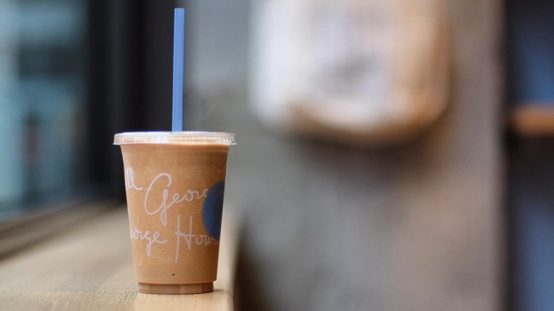 Iced coffee in a plastic to-go cup with a straw sits on a countertop