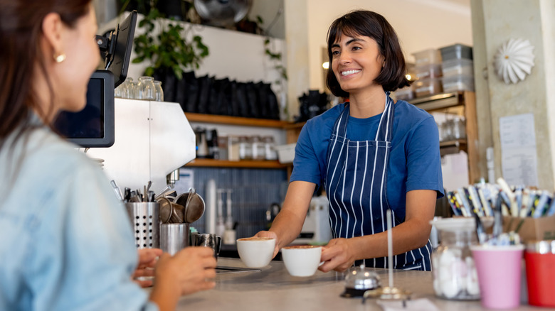 Barista serving coffee mugs at a coffee shop