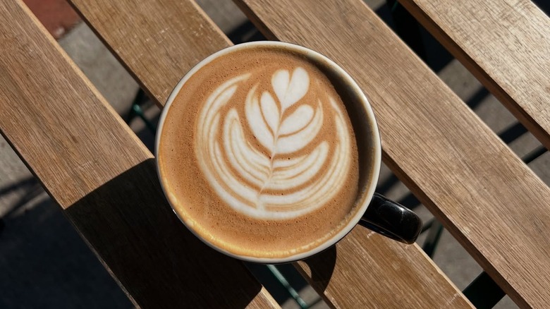 Mug of coffee with latte art sits on a wooden table