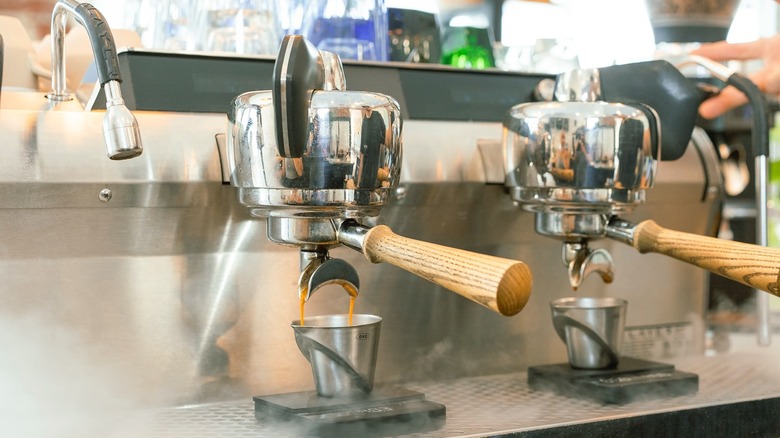 Coffee pours from a dual-spout portafilter into a metal cup