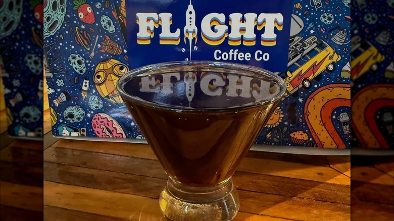 Coffee beverage in a glass sits in front of a graphic that reads "Flight Coffee Co"
