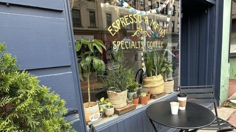 Coffee cups sit on a table outside the entrance to Espresso a Mano