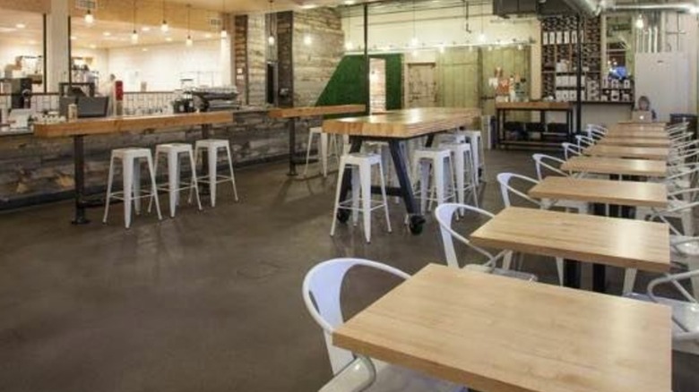 Row of empty tables and white chairs inside the Publik Coffee shop