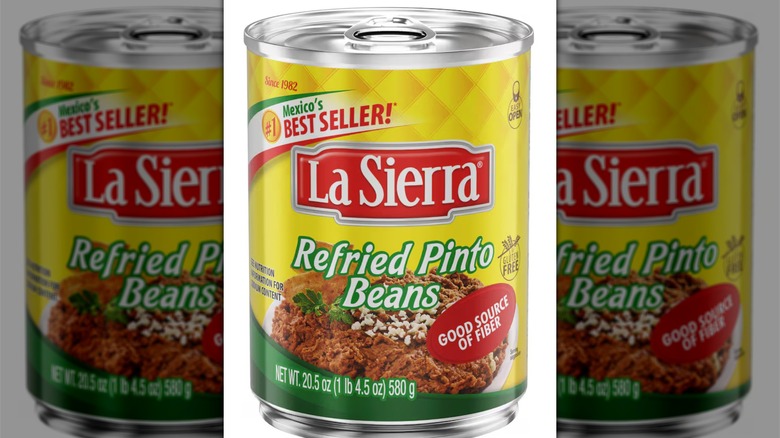 Yellow can of La Sierra refried pinto beans on a white background