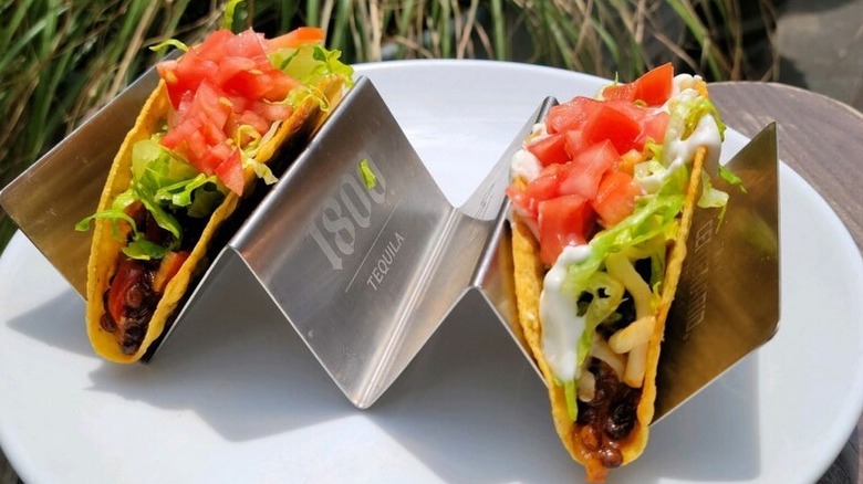 Two tacos in metal holder at El Barrio Restaurante