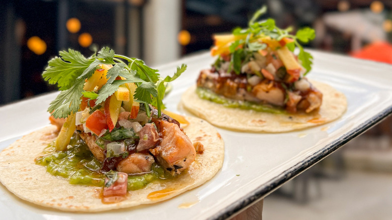 Two open tacos topped with meat and vegetables from Camacho Garage
