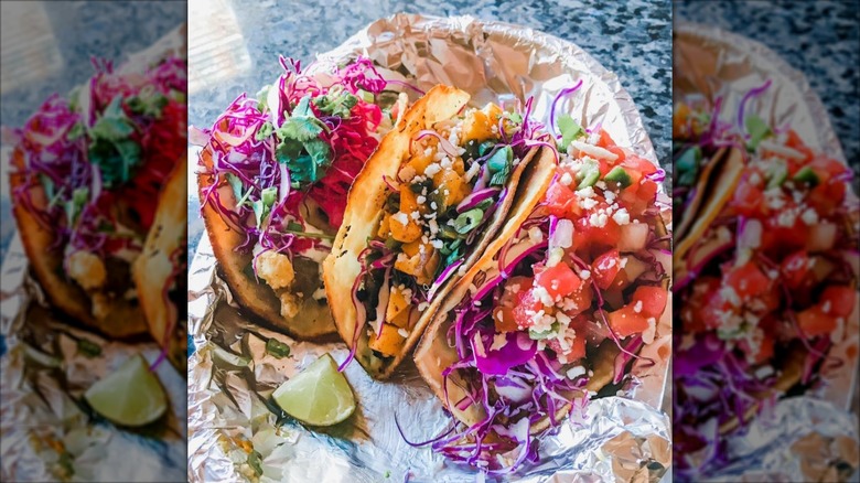 Three colorful tacos on foil at Taco Escobarr