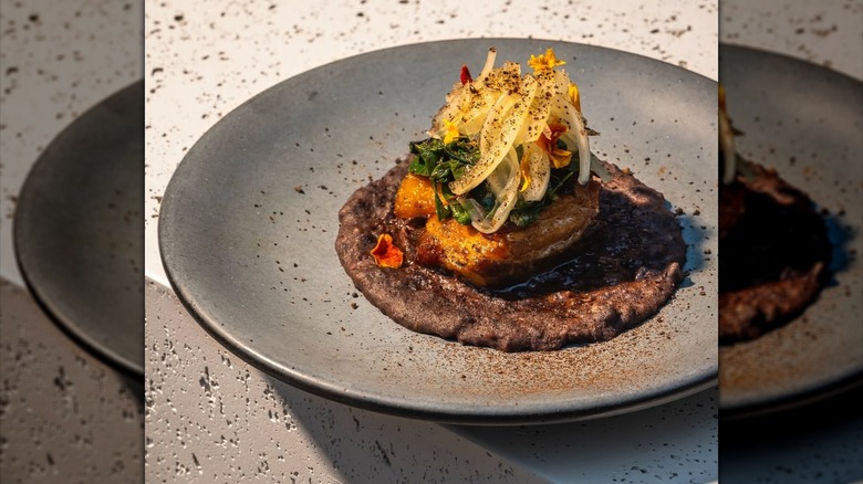 A dish called Frijol Con Puerco expertly presented on a plate