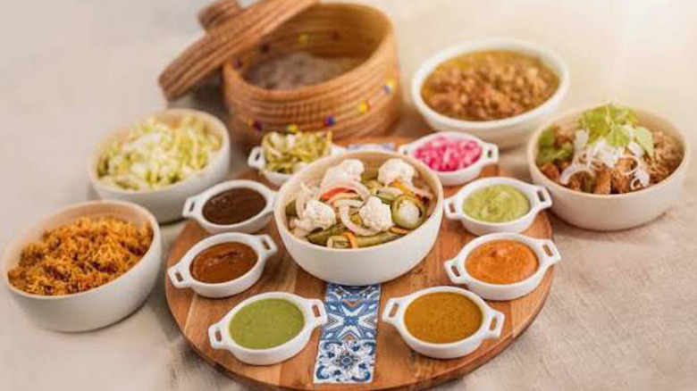 Several Mexican dishes and sauces on small plates and bowls, with fajitas in basket