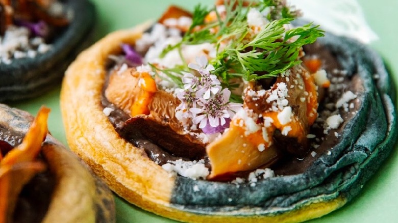 a handcrafted Mexican pastry topped with small greens and flowers