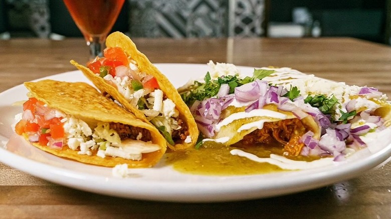 hard shell and soft shell saucy tacos on plate on wooden table