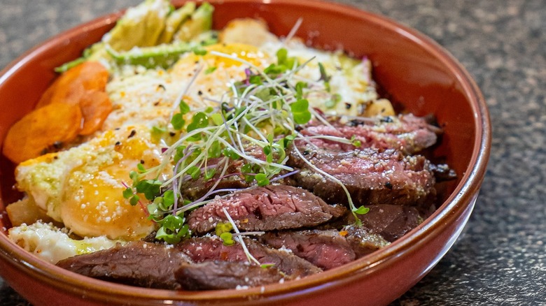 Citrus marinated beef, with round fried potatoes, scrambled eggs, and cheese in deep plate