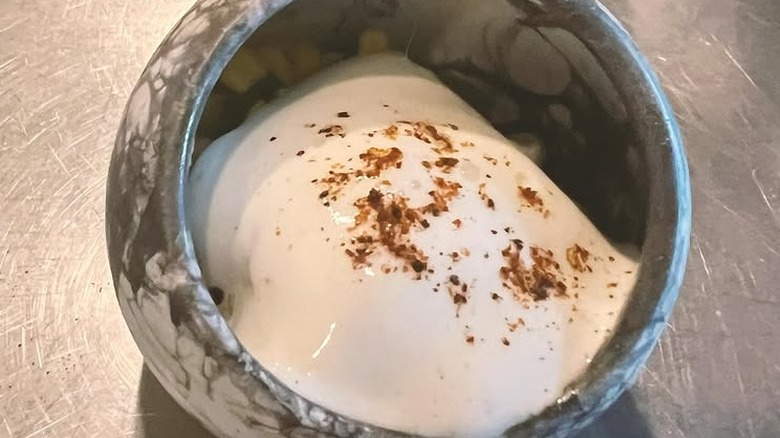 creative Meixcan dish with cheese foam, white corn esquites, and lobster topped with chile and served in marble bowl