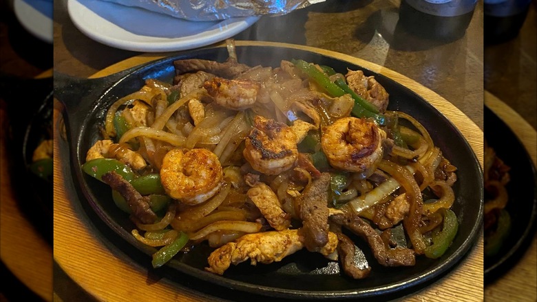 Steak and shrimp fajitas served with onions and pepers on hot plate at restaurant
