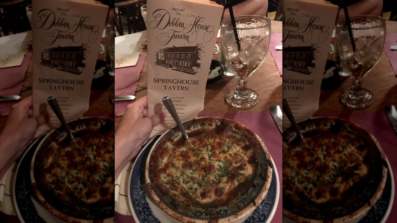 Hand holding Dobbin House Tavern menu behind French onion soup