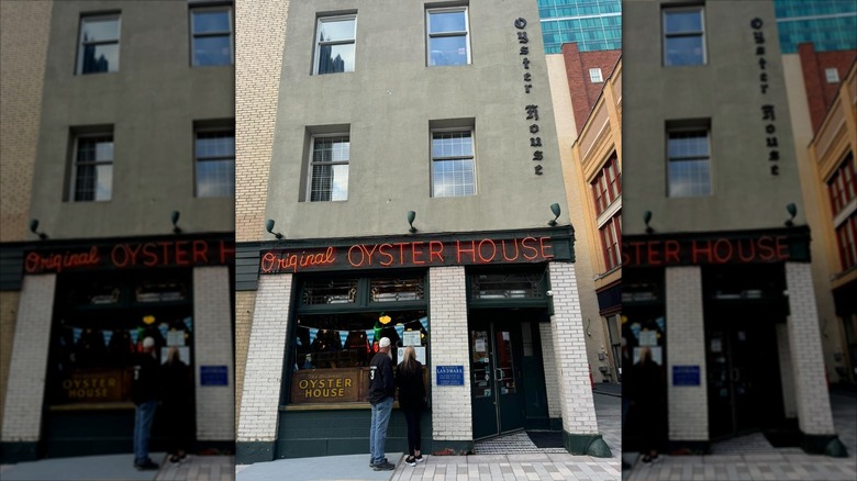 Two people look at the menu on the wall outside The Original Oyster House Pittsburgh