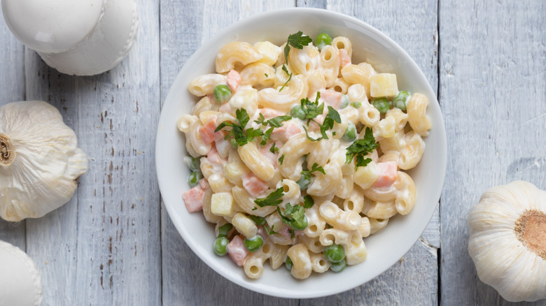 macaroni salad in bowl with garlic heads on table