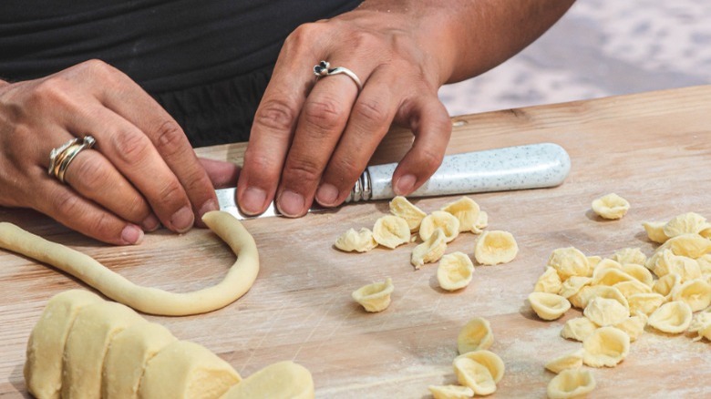 Person shaping orecchiette with hands and knife
