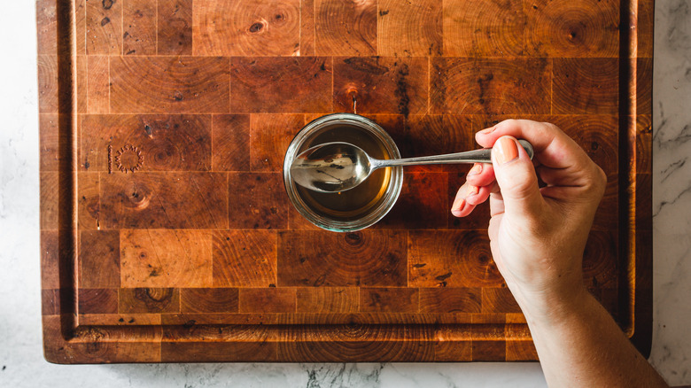 A person spoons out apple cider vinegar from a jar