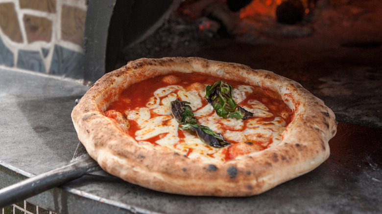 Pulling pizza out of brick oven with pizza peel