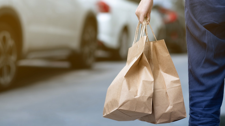 person carrying take-away food in brown bags