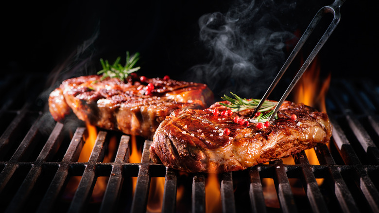 Steaks cooking over fire on a grill