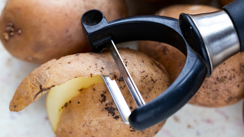 potatoes and a potato peeler 