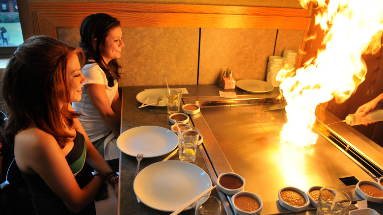 Two ladies watching someone grill on a hibachi grill