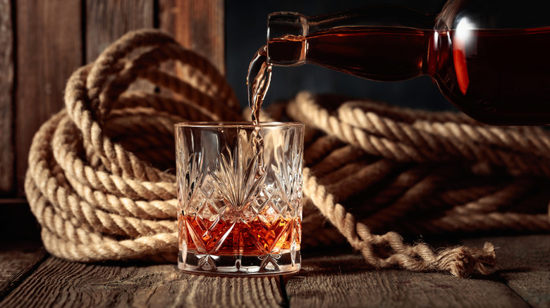 dark rum being poured into a glass with rope in the background