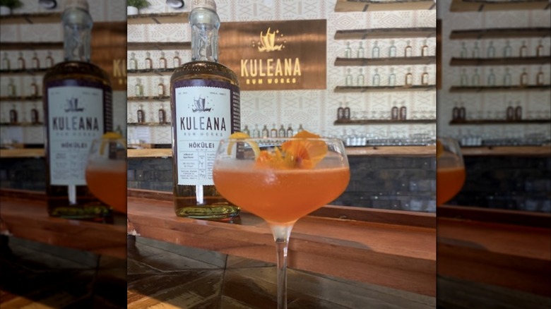 bottle of Kuleana Hōkūlei on bar behind cocktail