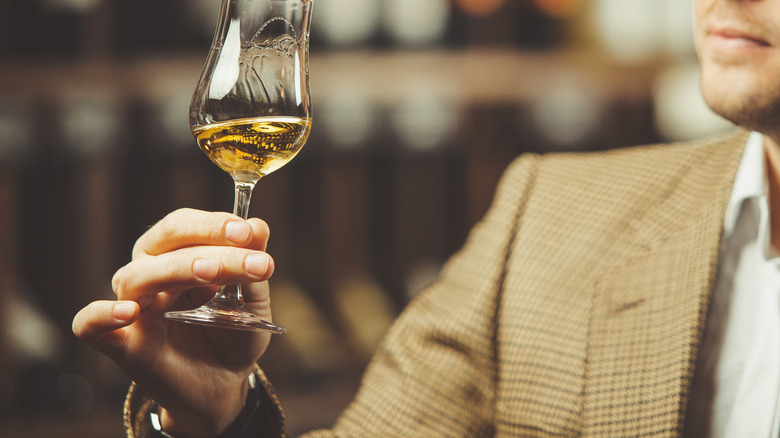 Man in suit examines whiskey