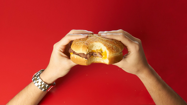 Woman eating Wendy's burger on red background