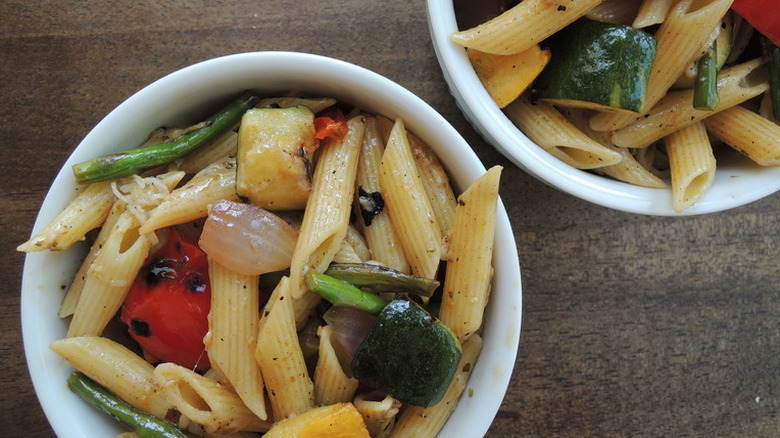 Two white bowls of grilled summer vegetable pasta salad