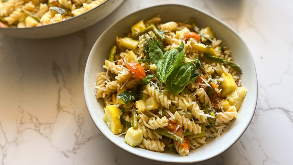 pasta primavera with noodles zucchini and tomato in white bowl