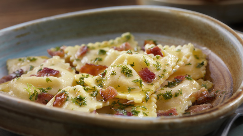 Ravioli with bacon and parsley in ceramic bowl