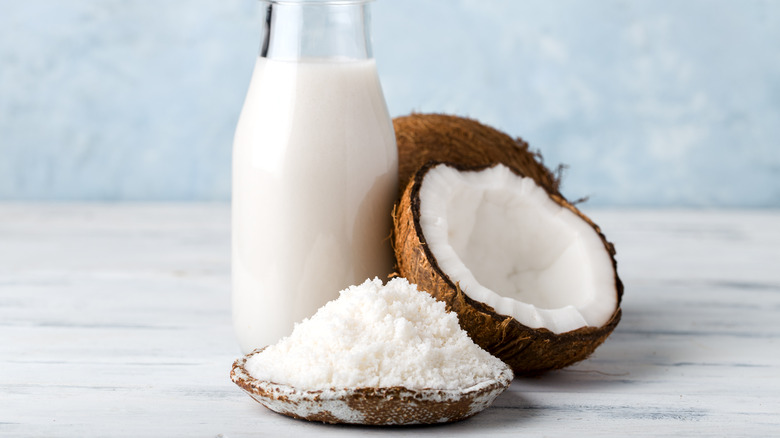 Halved coconut next to coconut flour and coconut milk