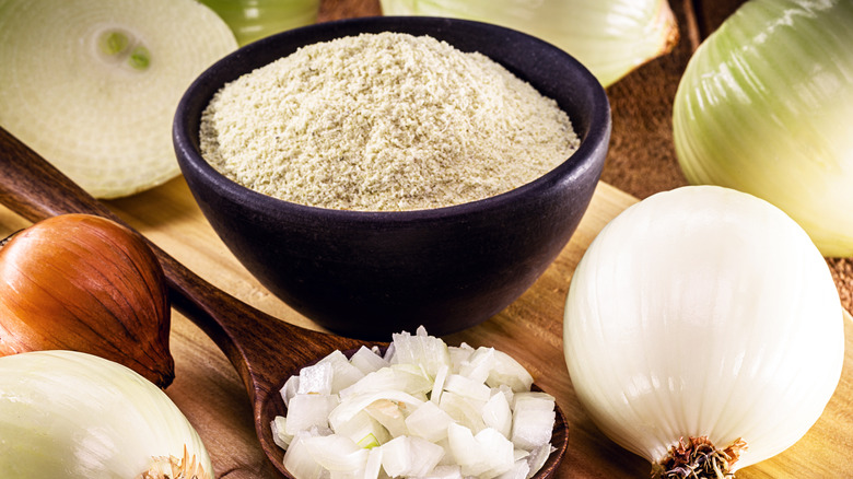 A bowl of onion powder with onions in the background 